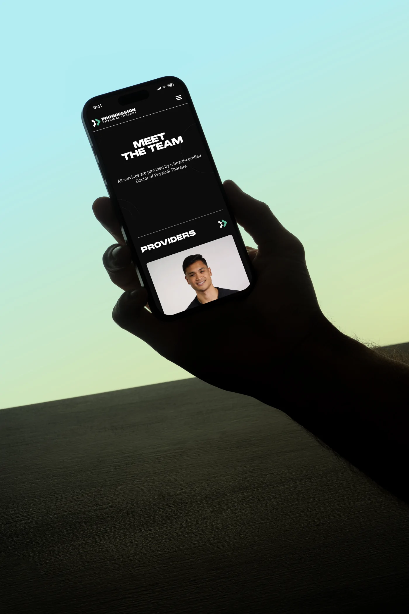 The Meet the team page on a phone held against a soft sky