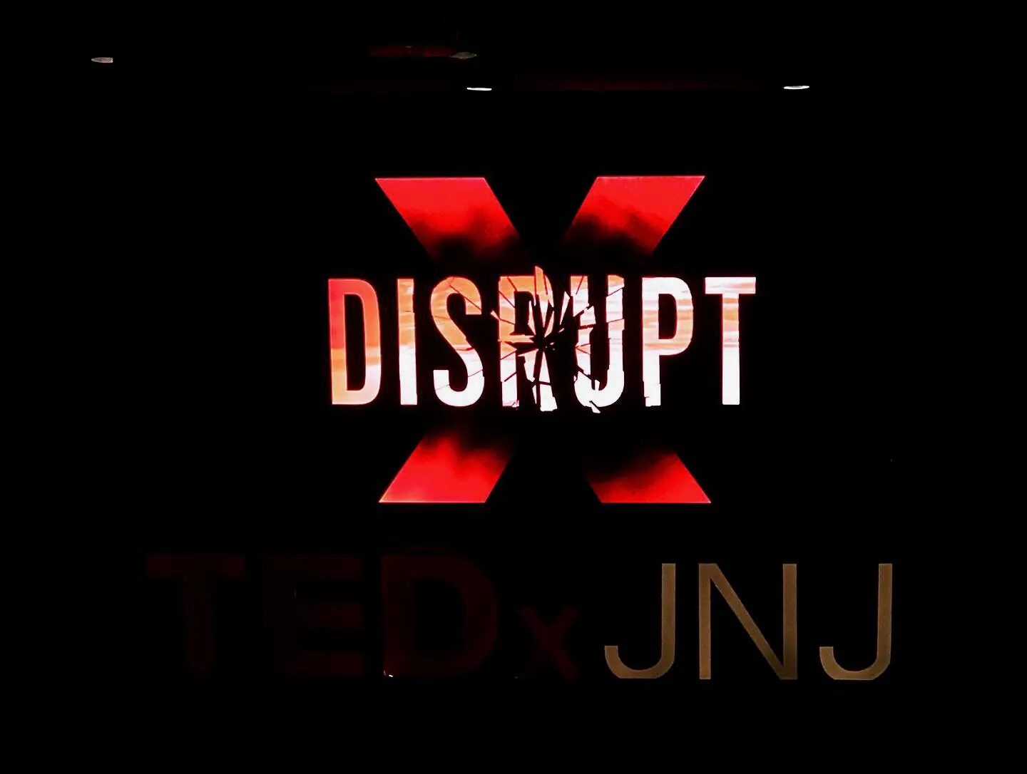 The Disrupt logo: the word over a red X, above the TEDxJNJ wordmark